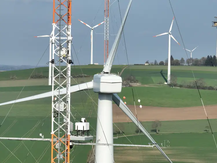 Lidar system on the platform of a meteorological measuring mast at hub height. The nacelle and rotor star of the research wind turbine can be seen in the background.