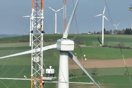 Lidarsystem auf der Plattform eines meteoroligschen Messmastes in Nabenhöhe. Im Hintergrund sind die Gondel und der Rotorstern der Forschungswindenergieanlage zu sehen.